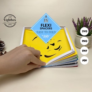 May include: A multi-layered paper art piece with a yellow background and black cut-out shapes. The text "FLEXI SPACERS EASY TO FOLD" is displayed on a blue diamond. The image also includes SVG, PNG, DXF, and PDF file type icons.
