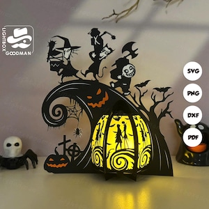 May include: Black Halloween-themed paper cut-out decoration featuring silhouettes of characters, a jack-o'-lantern, and a glowing lantern. The design includes bats, a spider web, and a tombstone. The lantern is lit from within, creating a warm glow.