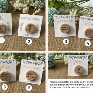 May include: A collection of six small, white cards with wooden bottle stoppers. Each card features the word "MERCI" or names, dates, and decorative elements. The stoppers have engraved designs, including hearts and arrows.