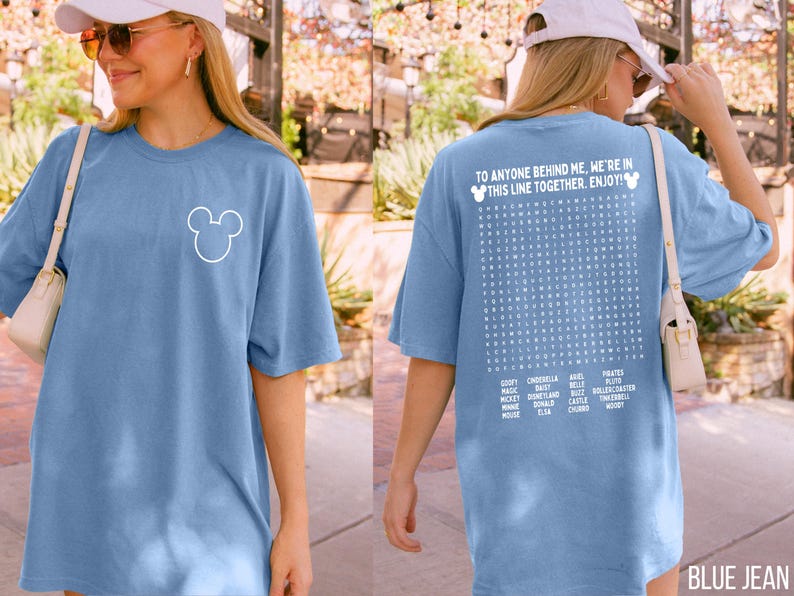 May include: A blue jean colored t-shirt with a white Mickey Mouse outline on the front. The back of the shirt features the text "TO ANYONE BEHIND ME, WE'RE IN THIS LINE TOGETHER. ENJOY!" and a word search with Disney-related words.