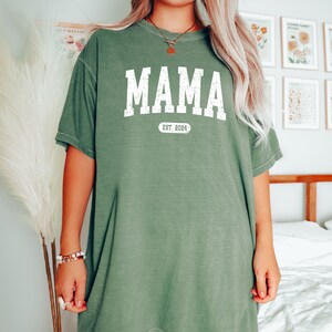 May include: A green oversized t-shirt with the text "MAMA EST. 2024" in white.