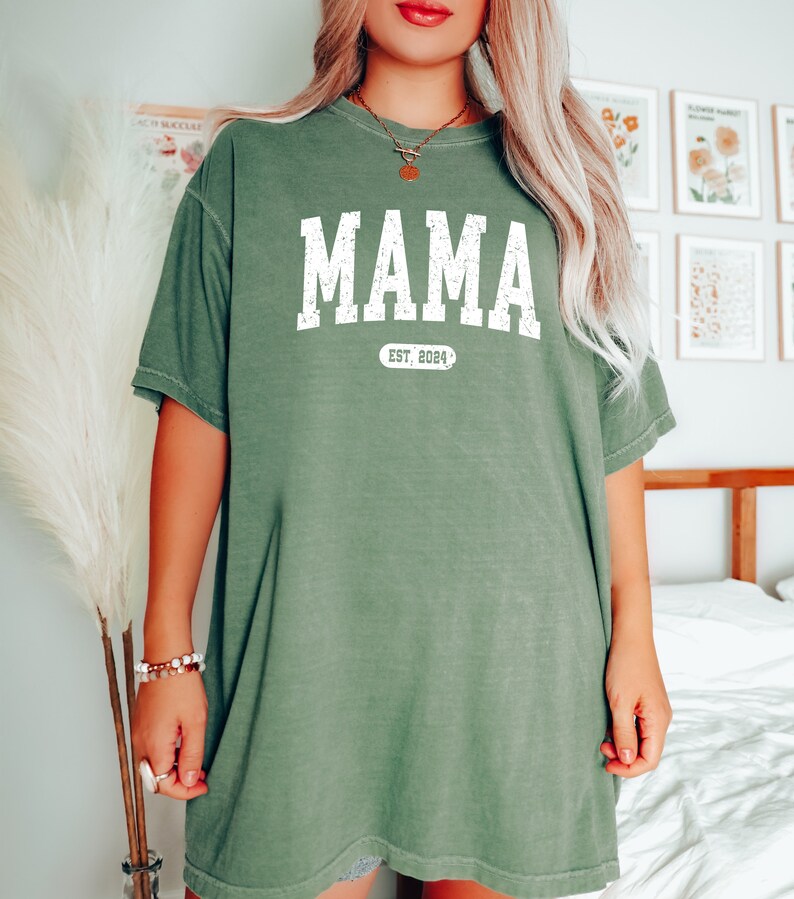 May include: A green oversized t-shirt with the text "MAMA EST. 2024" in white.
