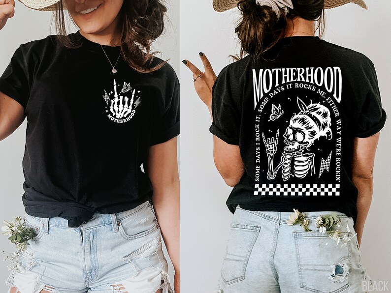 May include: Black t-shirt with a white graphic of a skeleton with a butterfly and the text "MOTHERHOOD SOME DAYS I ROCK IT, SOME DAYS IT ROCKS ME. EITHER WAY WE'RE ROCKIN'"