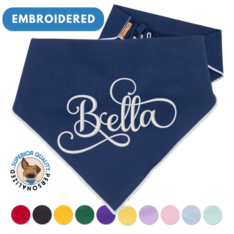 May include: Navy blue dog bandana with white embroidered text "Bella" and a white border. The bandana is folded in half and has a white label with the text "Superior Quality Personalized". The image also shows a variety of colors for the bandana.