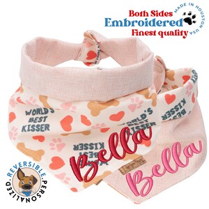 May include: A pink and beige reversible dog bandana with paw prints and hearts. One side says "World's Best Kisser" and the other side is personalized with the name "Bella".