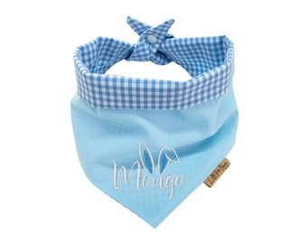 May include: A light blue dog bandana with a white gingham trim and a white embroidered bunny with the name "Mongo" on it. The bandana has a brown label with the text "Little Fox Pet".