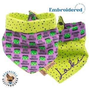 May include: Reversible dog bandana with a green and purple pattern. One side features a repeating pattern of green monsters with the text "Little Monster" on a purple background. The other side is green with black polka dots and the name "Loki" embroidered in purple. The bandana is made in the USA.