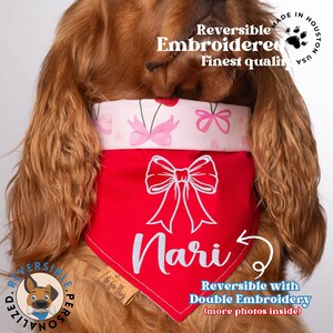 May include: A red and pink reversible dog bandana with a white bow and the name "Nari" embroidered on it. The bandana is made in the USA and features double embroidery.