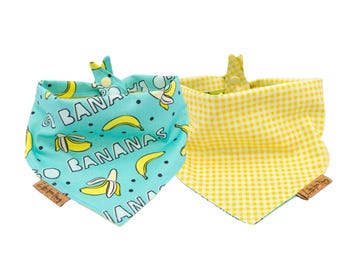 May include: Two turquoise and yellow bandana bibs with a gingham pattern and a banana print. One bib has the text "BANANAS" on it.