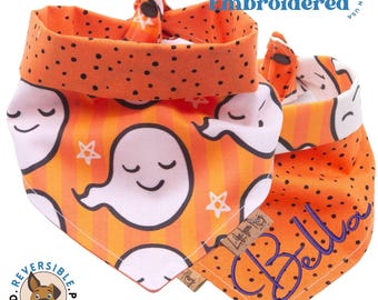 May include: Reversible dog bandana with a ghost pattern on one side and orange polka dots on the other. The polka dot side has the name "Bella" embroidered in purple.