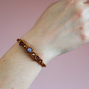 May include: A brown bracelet with purple stones and gold accents.