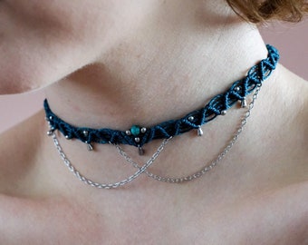 May include: A dark blue choker necklace with a silver chain and turquoise beads. The choker is made of a braided cord and has a delicate, feminine design.