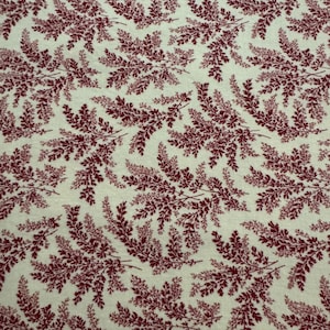 May include: Cream-colored fabric with a repeating pattern of burgundy-colored fern-like branches. The branches are detailed with small leaves, creating a textured appearance. The design is evenly distributed across the fabric.