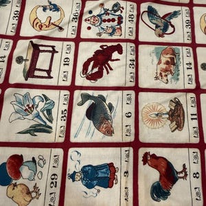 May include: Cream-colored fabric with a repeating pattern of rectangular cards. Each card features a different illustration, including a lobster, a fish, a rooster, and a clown. The cards are outlined in red.