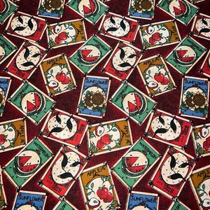May include: A red fabric with a repeating pattern of seed packets. The packets are in various colors and feature illustrations of apples, watermelons, sunflowers, and birds. The text on the packets includes "APPLE", "WATERMELON", "SUNFLOWER", and "BIRD".