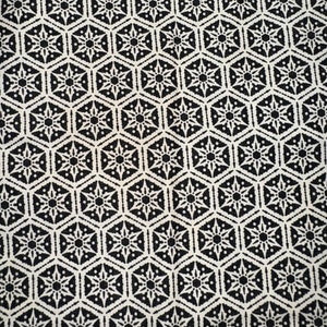 Peut inclure: Tissu noir et blanc avec un motif géométrique répétitif de formes hexagonales avec un motif en étoile au centre de chaque hexagone.