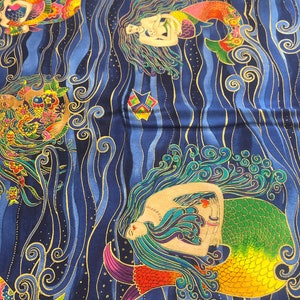 Könnte beinhalten: Ein blauer Stoff mit einem goldenen und farbenfrohen Design von Meerjungfrauen, die in Wellen schwimmen. Die Meerjungfrauen haben langes, fließendes Haar und halten einen kleinen Fisch oder eine Meereskreatur.