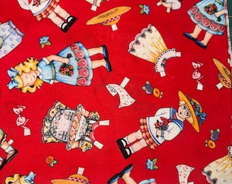 May include: Red fabric featuring vintage paper doll illustrations. The design includes dolls in sailor outfits, dresses, and hats, along with floral and candy accents. The fabric has the text "Mary & Co. for VIP by Cranston®".