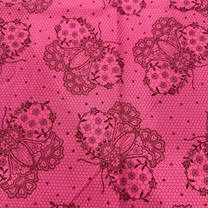 Pode incluir: Close-up de um tecido rosa vibrante com um padrão repetido de desenhos de borboletas marrons escuras. As borboletas são detalhadas com elementos florais e rendados, sobre um fundo de favo de mel.