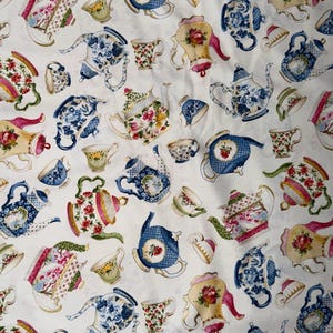 Puede incluir: Tela blanca con un estampado repetido de teteras y tazas en varios colores. Las teteras y tazas presentan diseños florales, patrones azules y blancos y detalles dorados. Un diseño encantador para los amantes del té.