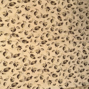May include: Cream-colored fabric with a repeating pattern of dark brown floral and leaf motifs. The design features stylized flowers and foliage, creating a vintage or botanical aesthetic. The fabric appears to be a cotton or linen blend.