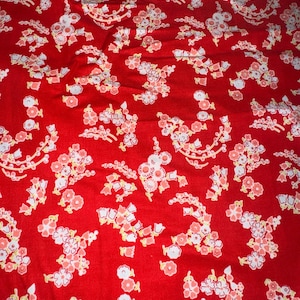 May include: Red fabric with a white and pink floral pattern. The flowers are arranged in clusters and have a vintage style.