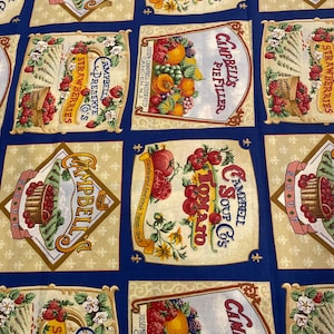 May include: A blue fabric featuring a repeating grid pattern of vintage Campbell's Soup and Preserve labels. Each rectangular section displays illustrations of tomatoes, strawberries, and assorted fruits with text including Campbell's Soup Co.