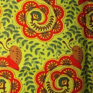 Pode incluir: Close-up de um tecido com um padrão repetitivo de motivos florais e foliares estilizados. O design apresenta grandes formas florais vermelhas e castanhas com centros amarelos, sobre um fundo verde claro. Pequenas folhas verdes preenchem os espaços.