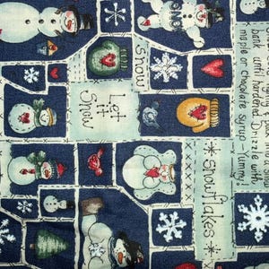 May include: A winter-themed fabric with a repeating pattern of snowmen, snowflakes, hearts, and mittens on a navy blue background. The fabric also features text that reads "Snow Ice Cream" and "Let it Snow".