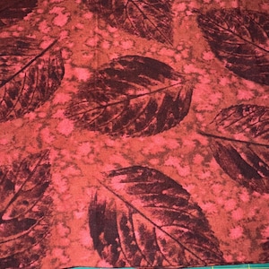 May include: Red fabric with a dark brown leaf pattern. The fabric is textured and has a slightly mottled appearance.