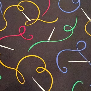 May include: Black fabric with a repeating pattern of colorful thread and needles. The thread is in yellow, red, green, and blue, with white needles scattered throughout. The design is suitable for sewing projects.