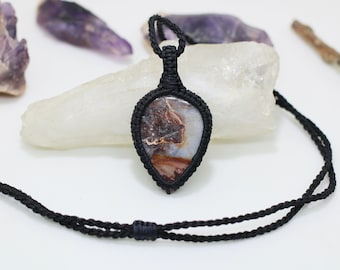 Könnte beinhalten: Eine schwarze Schnurkette mit einem tropfenförmigen Anhänger aus braunem, weißem und goldenem Achat.