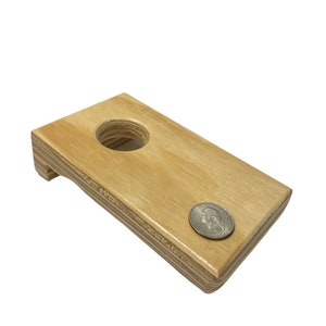 May include: A wooden game board with a hole in the center. A US quarter is resting on the board to show the size of the hole.