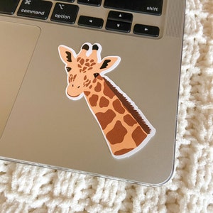 May include: A sticker of a giraffe's head and neck with brown spots on a light brown background. The giraffe is looking to the left.