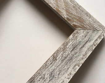 May include: A whitewashed wooden picture frame with a distressed finish. The frame is made of thick wood and has a rustic look.