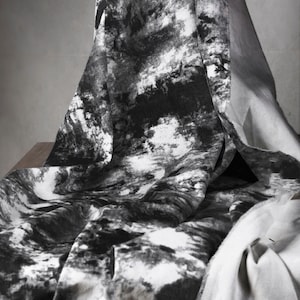 Könnte beinhalten: Schwarz-weißes abstraktes Mustergewebe mit weicher, strukturierter Haptik. Der Stoff ist gefaltet und über eine Oberfläche gelegt.