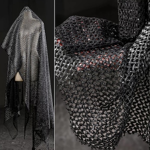 Puede incluir: Tela de malla negra con un acabado brillante. La tela está drapeada sobre un maniquí y colocada plana sobre una superficie.