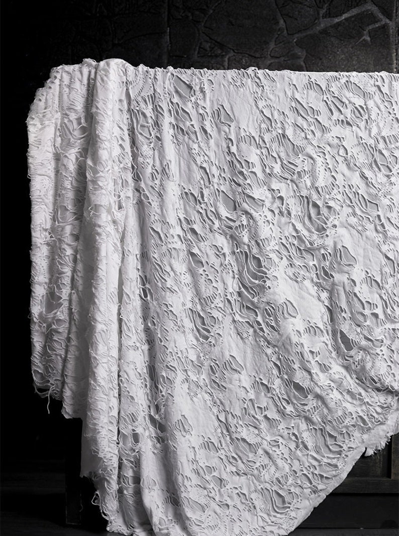 May include: White fabric with a distressed, ripped, and torn pattern. The fabric has a lace-like appearance with large holes throughout.