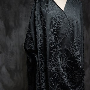 May include: Black fabric with a subtle embossed pattern of branches. The fabric has a silky sheen and a soft drape.