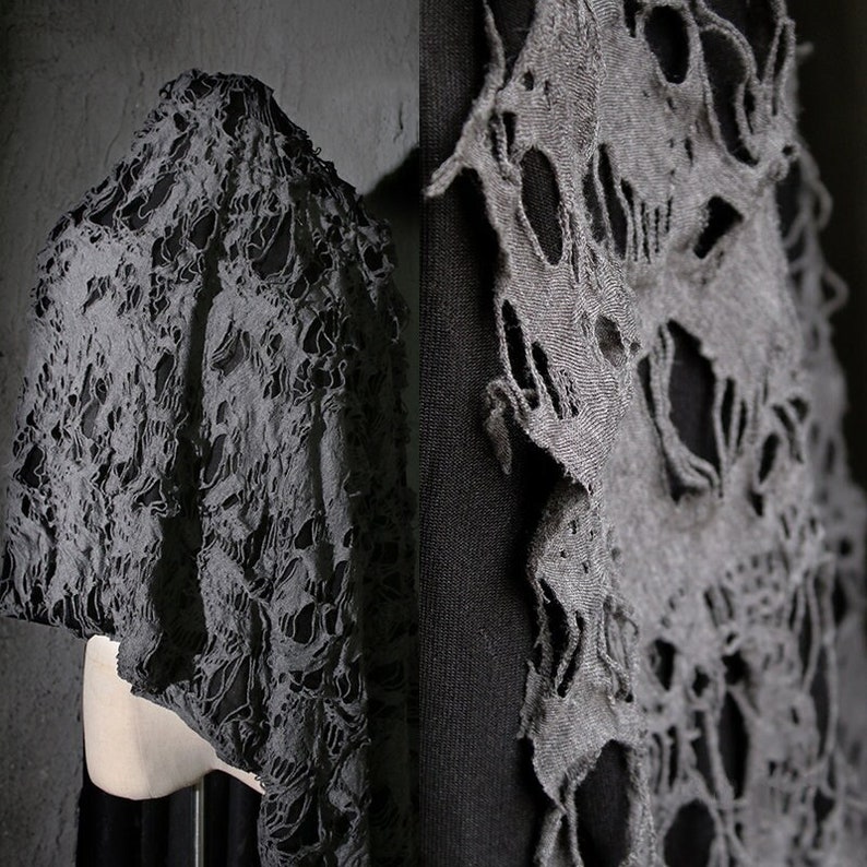May include: Gray hooded garment with a skull pattern, the fabric is distressed and has holes throughout.