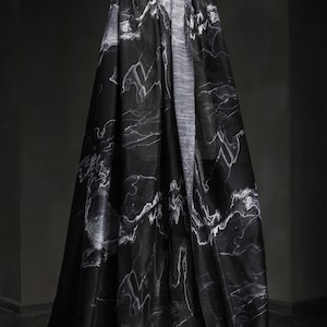 Könnte beinhalten: Schwarzer Stoff mit einem weißen Marmormuster, das über eine Schaufensterpuppe drapiert ist.