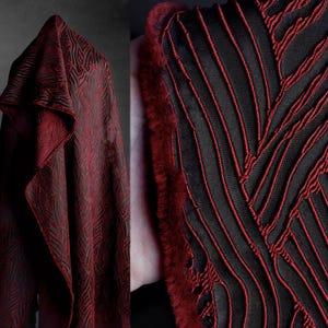 Può includere: Tessuto drappeggiato con un motivo geometrico rosso scuro e nero. Il tessuto ha un aspetto strutturato con un design ripetuto. Un primo piano rivela un tessuto nero con cuciture rosse e un bordo in pelliccia rossa.