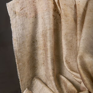 May include: A close-up of a beige fabric with a textured pattern and brown stains.