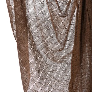 May include: A brown, sheer fabric with a woven pattern. The fabric is draped and folded, creating a textured look.