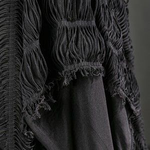 Puede incluir: Tela negra con un dise&ntilde;o texturizado y fruncido. La tela est&aacute; recogida y drapeada, creando un look fluido y dram&aacute;tico.