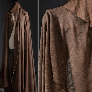 May include: A brown linen fabric with a textured weave. The fabric is draped and folded, showing the texture and drape of the material.