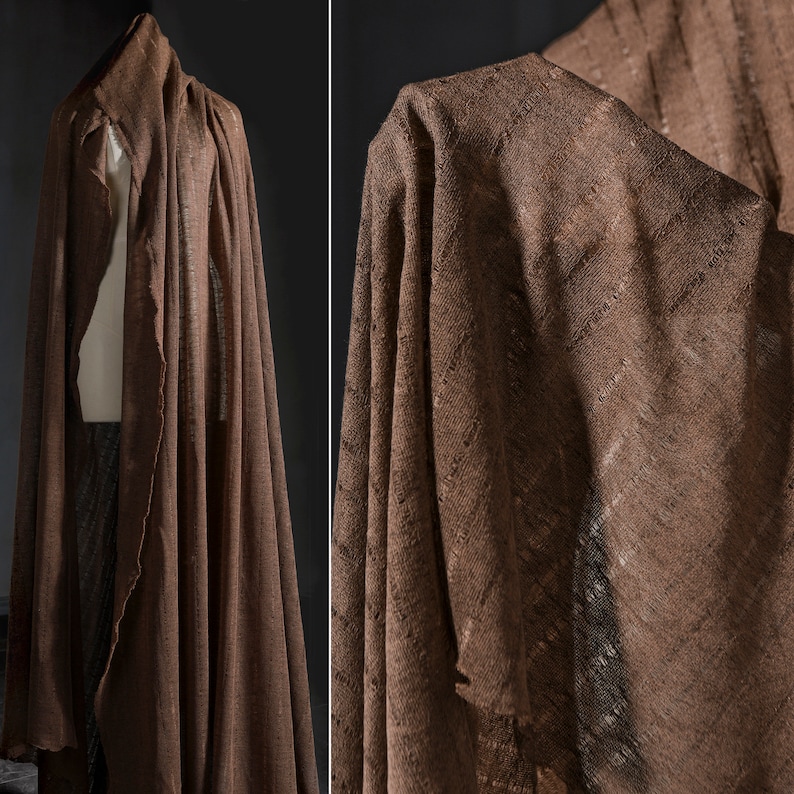 May include: A brown linen fabric with a textured weave. The fabric is draped and folded, showing the texture and drape of the material.