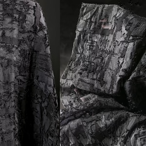 Könnte beinhalten: Ein schwarzes Kapuzenkleidungsstück aus strukturiertem, gemustertem Stoff. Der Stoff hat ein erhabenes, fast gewebtes Design.