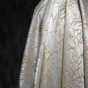 May include: White fabric with a raised embossed pattern of beige bamboo leaves.