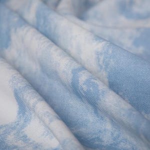Op de afbeelding: Close-up van een zachte, blauw-witte tie-dye stof met een gekreukelde textuur.